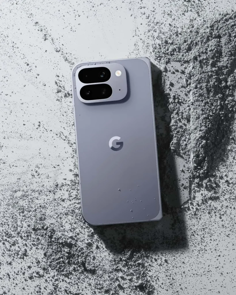Google Pixel 10 Pro Fold, in Moonstone, back view on grey sand with water droplets