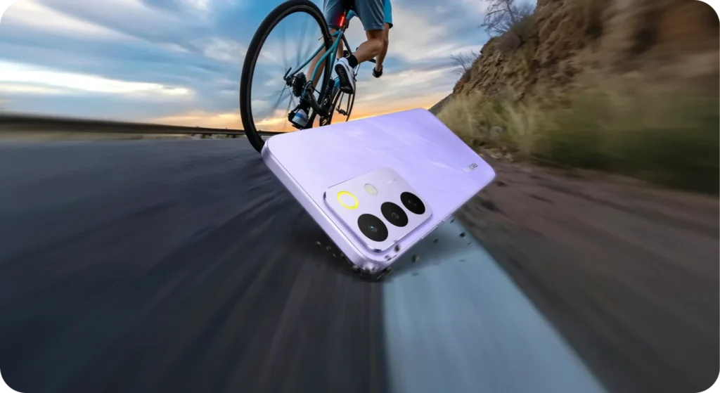 realme C85 5G, in Parrot Purple, on a road with a cyclist