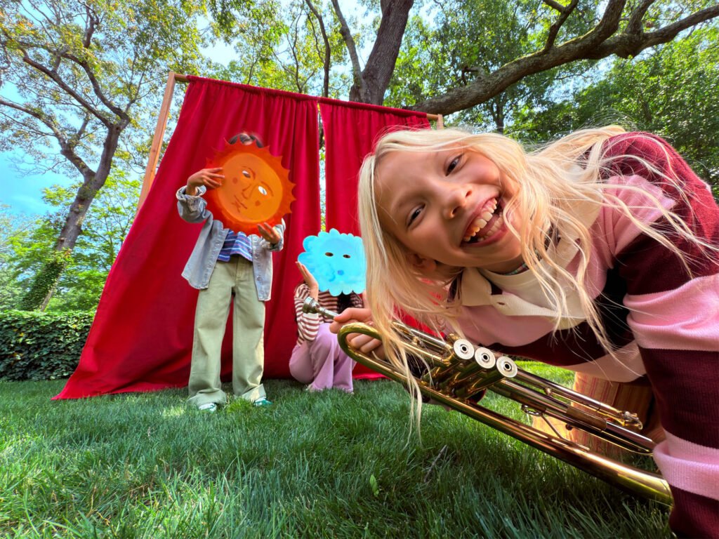Apple sample photo of children outdoors in front of a red curtain, taken with an ultrawide camera