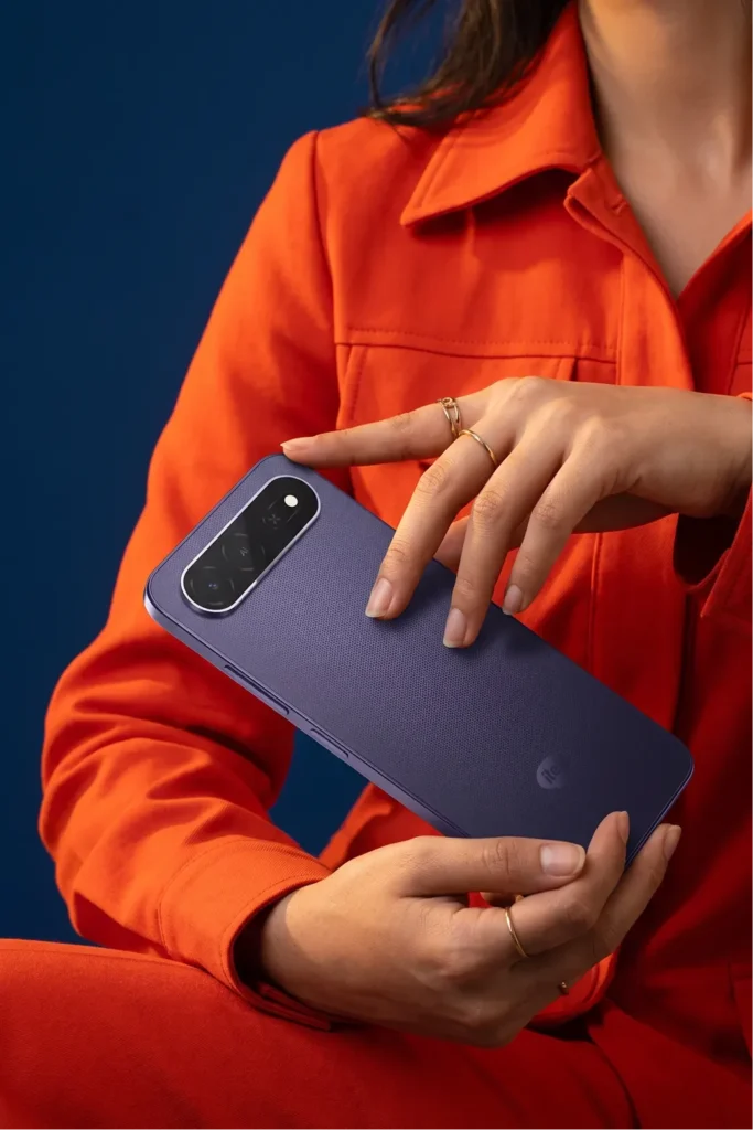 itel City 300 5G, held in both hands against an orange jacket
