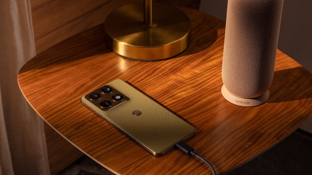 A green Motorola Signature lies face down on a wooden table, plugged into a charging cable