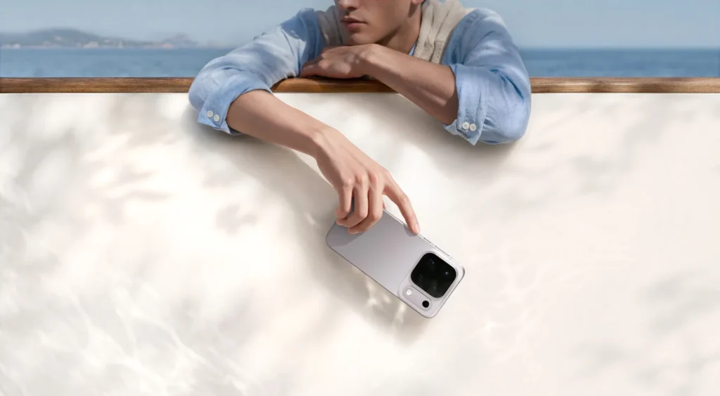 OPPO Find X10 Pro Max, in Titanium Grey, held over a sunlit white wall by the sea