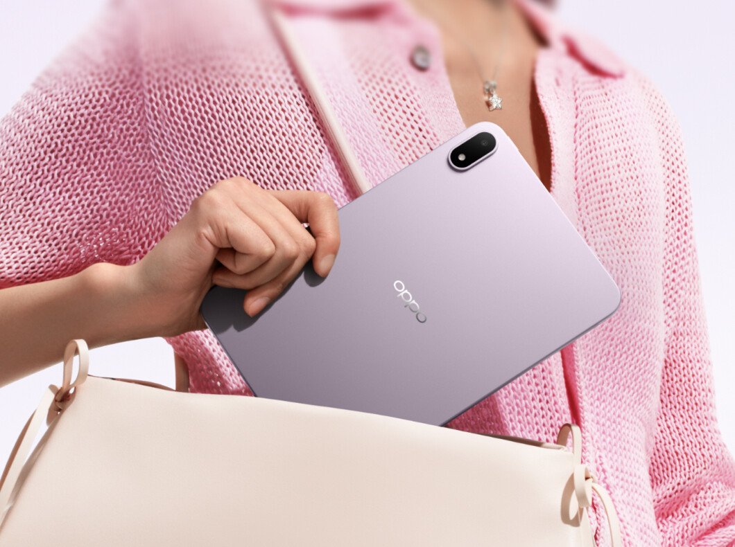 A hand slides the OPPO Pad Mini out of a cream handbag