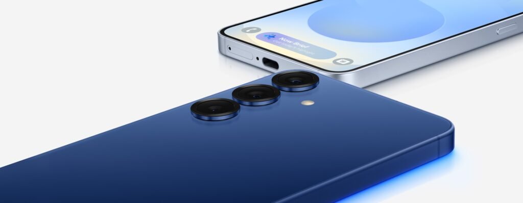 Samsung Galaxy S25 in navy blue lying on its back beside a second phone showing its screen and USB-C port