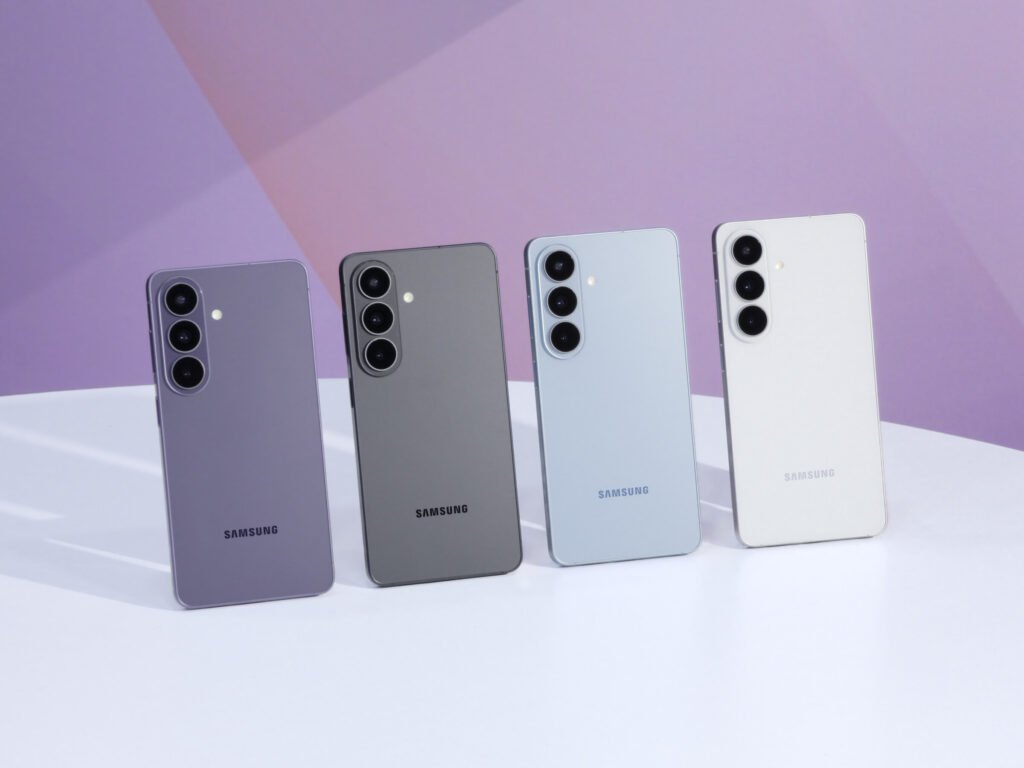 Four Samsung Galaxy S26 phones in violet, black, blue and white standing on a white table