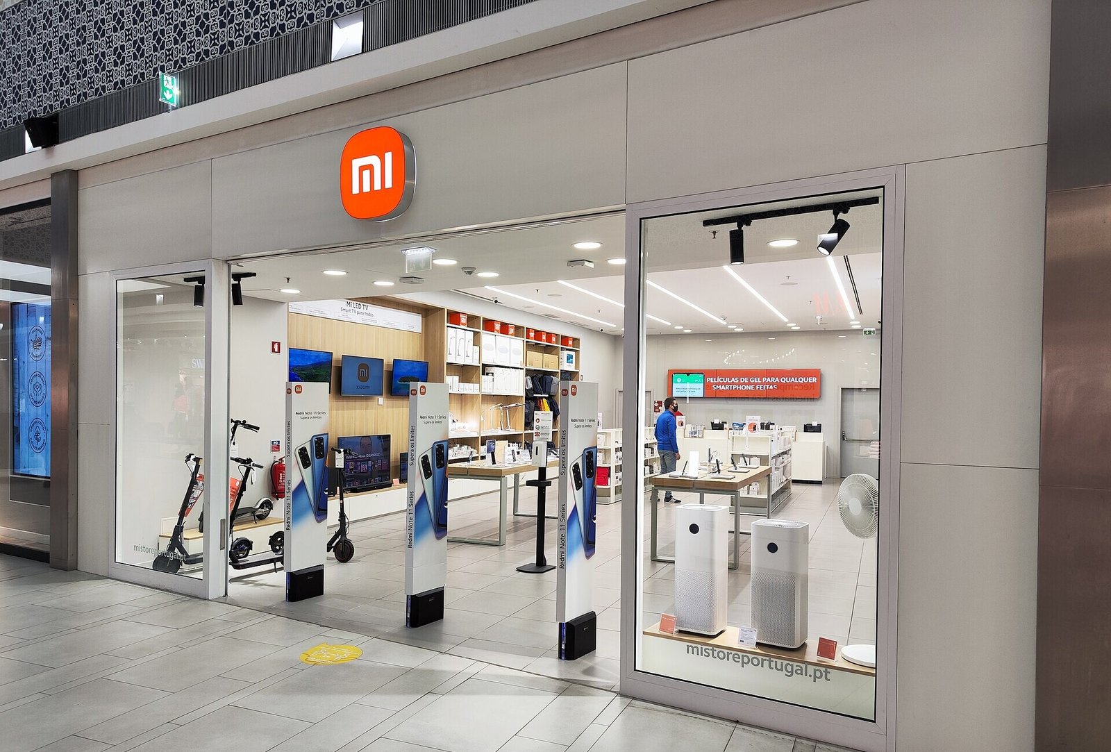 Front of a Xiaomi store in a shopping centre, with Redmi Note banners at the entrance and the orange Mi logo above the door